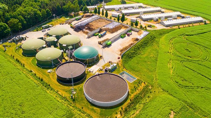 Aerial view of a modern biogas plant on farmland with anaerobic digesters and surrounding agricultural fields, representing renewable energy production in agriculture